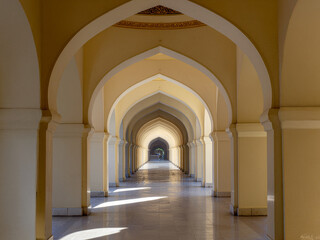 Fototapeta premium Perspective View of Islamic Mosque Arches Corridor with Dramatic Sunlight and Shadows