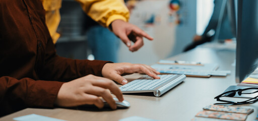 A dynamic scene of a creative workspace displaying a closeup of hands on a keyboard, highlighting collaboration and interaction among team members engaged in discussions. SACTR