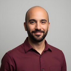 Confident portrait of a smiling young adult man in a maroon shirt against a clean neutral background, showcasing modern professional style, friendly expression, and studio lighting ideal for business 