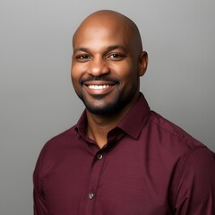 Confident portrait of a smiling young adult man in a maroon shirt against a clean neutral background, showcasing modern professional style, friendly expression, and studio lighting ideal for business 