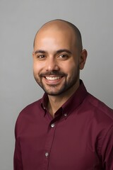 Confident portrait of a smiling young adult man in a maroon shirt against a clean neutral background, showcasing modern professional style, friendly expression, and studio lighting ideal for business 