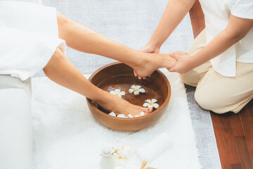 Woman indulges in blissful foot massage at luxurious spa salon while masseur give reflexology therapy in gentle day light ambiance resort or hotel foot spa. Quiescent
