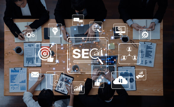 A diverse business team collaborates in a modern office, using various devices to analyze digital marketing strategies, focusing on search engine optimization and data insights. Trope