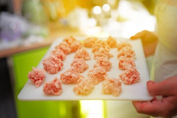 Woman carrying a plastic board with frozen meatballs on a bright sunny day for cooking