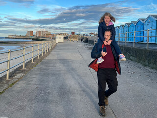 Father Carrying Daughter on Shoulders While Using Phone