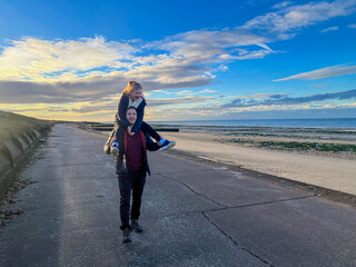 Father Carrying Daughter on Shoulders by the Beach
