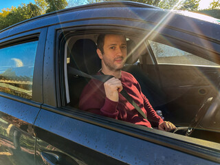 Man Fastening Seatbelt in Car on a Sunny Day