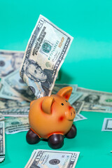 A twenty-dollar bill being placed into a piggy bank, surrounded by other bills, symbolizing savings and financial planning.