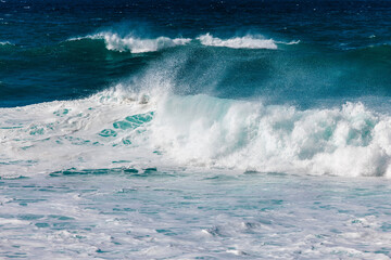 Powerful ocean waves crashing against the shore create a dynamic scene with foamy white surf and deep blue water, showcasing the beauty of nature's force and tranquility
