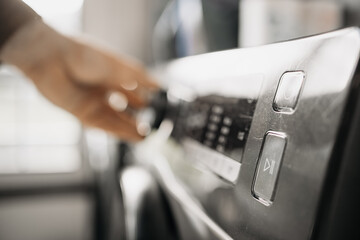 Close-up of a hand adjusting the settings on a modern washing machine control panel, showcasing sleek design and user-friendly interface for efficient laundry management