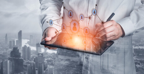 A business professional engages with a digital tablet to visualize social networks and connectivity in a contemporary urban setting with towering skyscrapers. Tessel