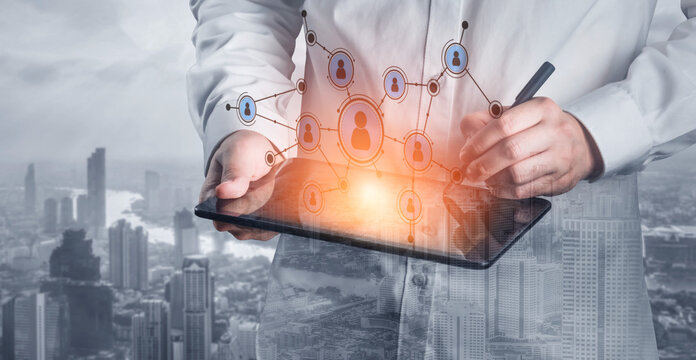 A business professional engages with a digital tablet to visualize social networks and connectivity in a contemporary urban setting with towering skyscrapers. Tessel