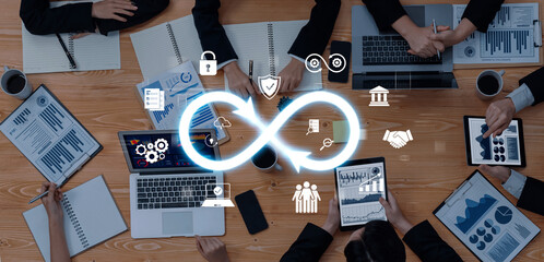 Business professionals engage in a collaborative strategy meeting, utilizing technology and data analysis tools on a wooden table in a modern office environment. Trope