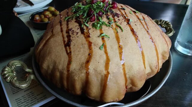 fancy elaborate fattoush salad inside a fried crispy pita bread shell being broken before eating with a spoon (middle eastern lebanese israeli syrian appetizer with pomegranate molasses and seeds)
