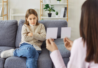 Psychologist showing visual cards to sad boy to evaluate development of empathy and understanding...