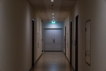 A green fire escape sign hangs from the ceiling, showing an exit sign green light box with a running man and an arrow pointing right for safety and evacuation.