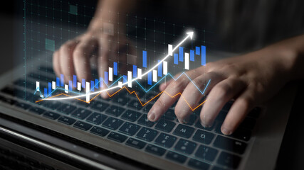 A close-up shot of hands typing on a laptop keyboard with an overlay of financial data visualization, including graphs and charts illustrating market growth and trends. Impute