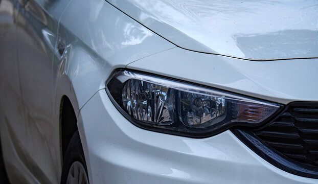 Side angle view of the front headlight and bumper of a white Toyota Corolla sedan highlighting the aerodynamic styling