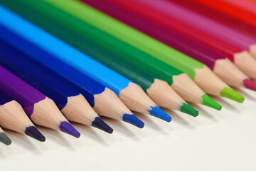 New wooden colored pencils of rainbow colors, perfectly sharpened, lie on table