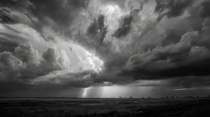Obraz premium Dramatic Black and White Lightning Strike Over Dark Clouds in Open Landscape during Stormy Weather with Evocative Atmosphere and Nature’s Power