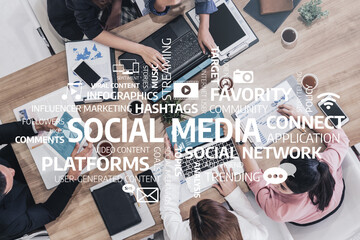 A diverse team collaborates in a modern office, focusing on social media strategies with laptops and engaging discussions, highlighting the importance of digital marketing. Tessel