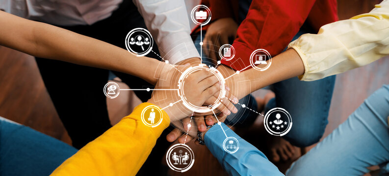 This image captures a diverse group of individuals uniting their hands in a collaborative gesture, symbolizing teamwork, support, and shared objectives within a professional setting. Amity