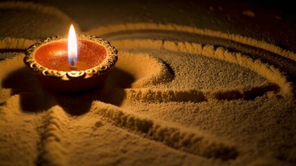 Closeup of a traditional Indian oil lamp diya glowing brightly on a sandy surface with intricate patterns symbolizing Diwali festivities and spiritual light.