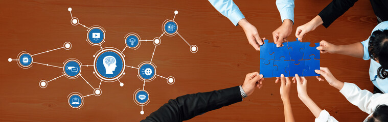 A group of diverse professionals collaborates at a wooden table, assembling puzzle pieces while...