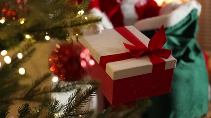 Santa Claus taking gift out of sack near Christmas tree at home, closeup
