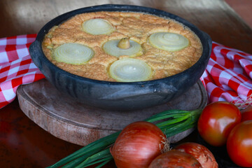 Traditional torta capixaba, a classic Brazilian seafood and vegetable pie typically served during Holy Week in Espírito Santo. Presented in a rustic clay pan, the dish features its iconic onion rings 