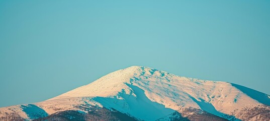 Dramatic snow capped mountain peak beneath a clear blue sky a winter sports adventure awaits