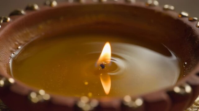 Close-up of a traditional Indian clay lamp, or Diya, with a burning wick and oil, used for religious ceremonies and festivals like Diwali, creating a warm and spiritual ambiance.
