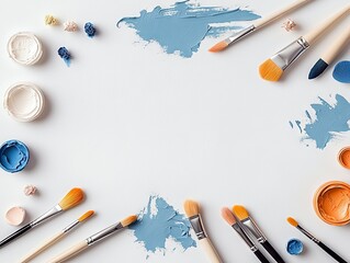 A collection of art supplies including paintbrushes, pots of white, blue, and orange paint, and smudges of blue paint are arranged on a white surface.