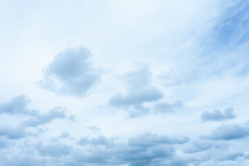 Pale blue and white overcast sky filled with scattered cumulus clouds moving slowly across the atmosphere
