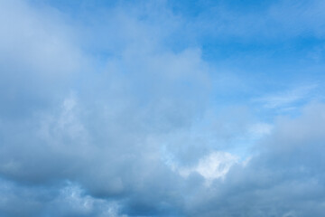 Blue sky background partially covered with thick dense gray and white clouds overhead