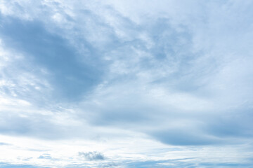 Wispy cirrus and cumulus clouds fill a pale blue sky with soft diffused daylight illumination