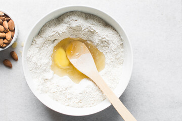 overhead view of almond biscotti dough being mixed in a white bowl, flatlay of biscotti cookie...