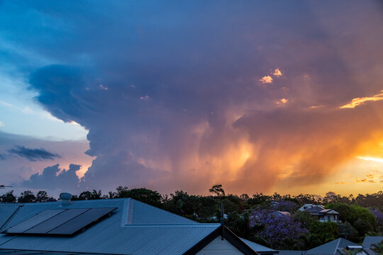 Colourful sunset storm clouds approaching suburban houses.