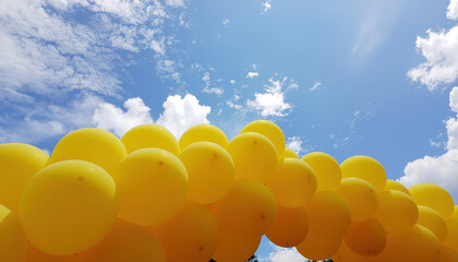 Yellow balloon background holiday sky celebration arch with bright yellow balloons under blue sky and scattered clouds creating cheerful festive scene