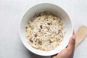Top view of homemade granola mix in a white bowl, prepping healthy granola breakfast bowl	