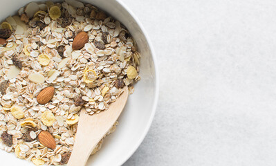 Top view of homemade granola mix in a white bowl, prepping healthy granola breakfast bowl	