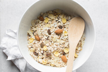 Top view of homemade granola mix in a white bowl, prepping healthy granola breakfast bowl	