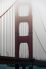 Tall vertical view of the Golden Gate Bridge rising into the fog.