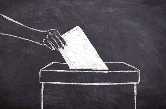 Hand-drawn chalk sketch on dark blackboard &ndash; hand casting envelope into ballot box, symbol of elections and democracy