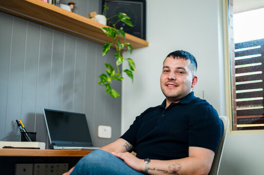 A man in his 30s sitting at a home desk with a computer