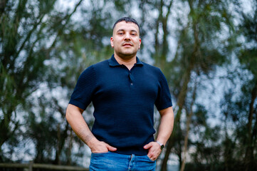 A man stands in a park with trees in the background, capturing the day’s light and warmth
