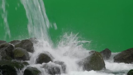 Powerful waterfall cascading over wet rocks creating a dynamic splash, isolated on a green screen for easy video compositing and special effects