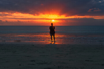 Silhouette of a man enjoying the sunset on the beach