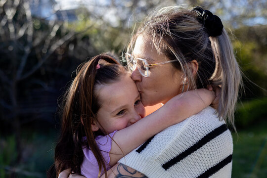 Mum hugging and giving daughter a kiss in the forehead