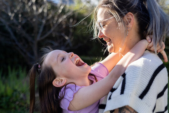 Mum hugging and giving daughter a kiss in the forehead